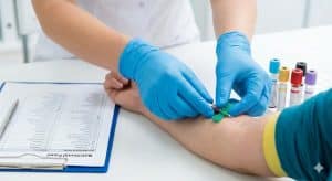 A close-up of a person's arm with a tourniquet getting a blood draw in a clinical setting.